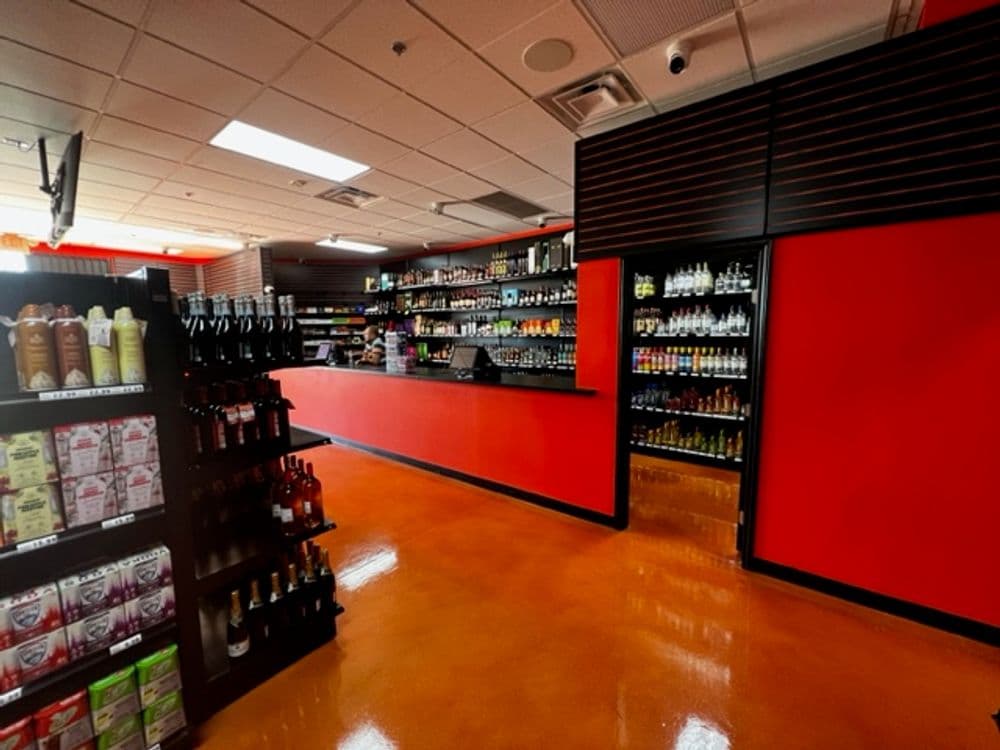Interior of a brightly lit convenience store featuring colorful shelves of drinks and snacks.