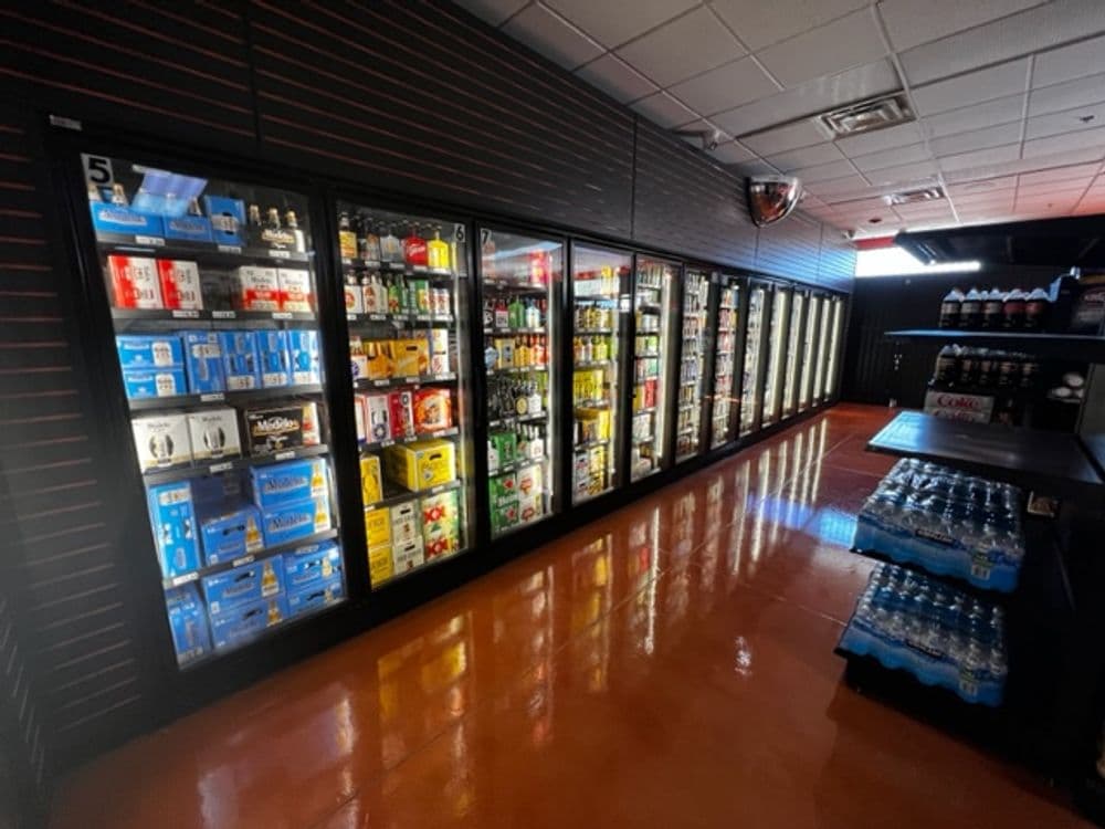 Cooler aisle displaying a variety of beverages in a well-lit store environment.