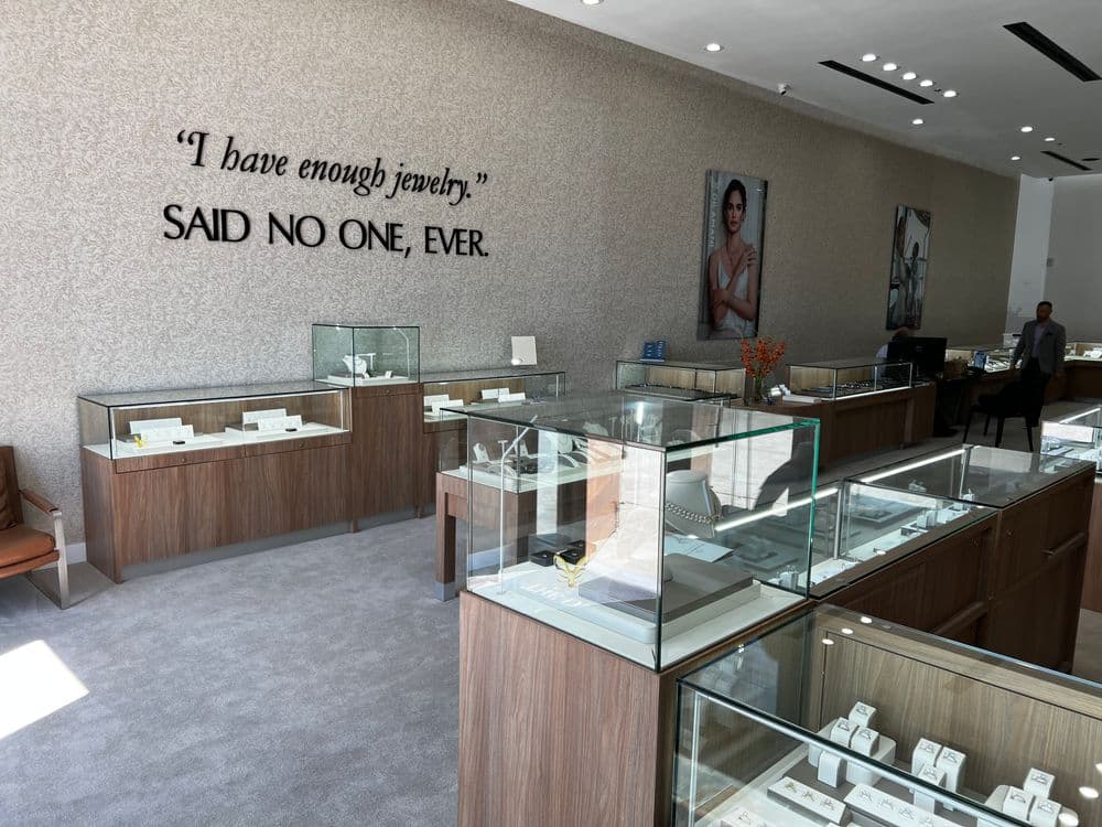 Jewelry store interior with display cases and humorous quote on the wall about jewelry desire.