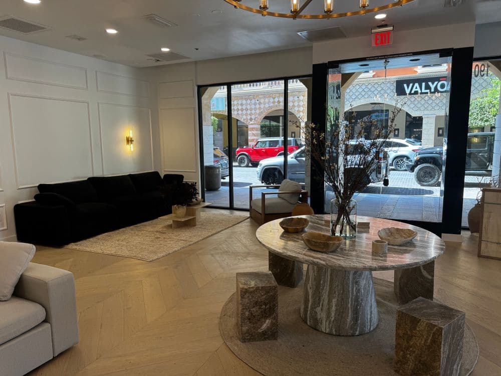 Modern interior design featuring a black sofa and a marble coffee table in a well-lit space.