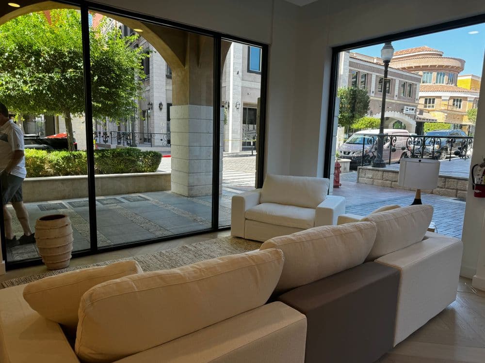 Spacious modern living room with a view of a stylish outdoor plaza and greenery.